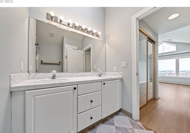 bathroom featuring double vanity, baseboards, and a textured ceiling