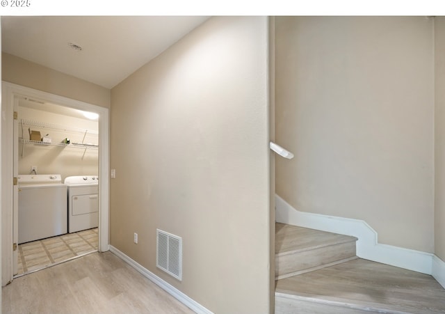 laundry room featuring washer and dryer, light wood-type flooring, and baseboards