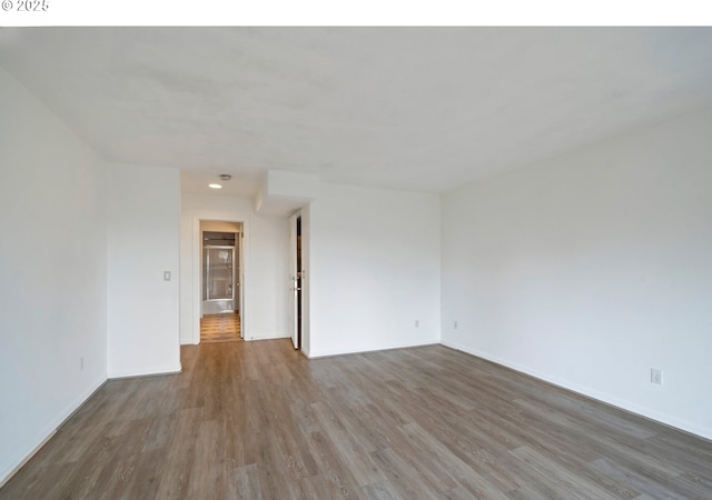 spare room with wood finished floors, baseboards, and recessed lighting