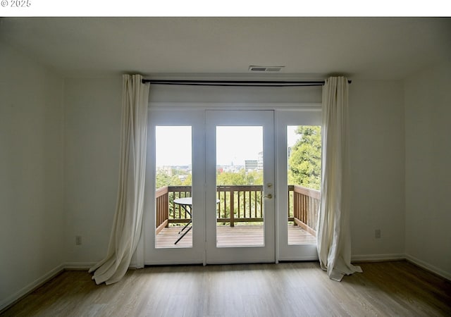 doorway to outside with healthy amount of natural light, wood finished floors, and baseboards