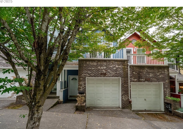 view of front of property featuring driveway, brick siding, and a balcony