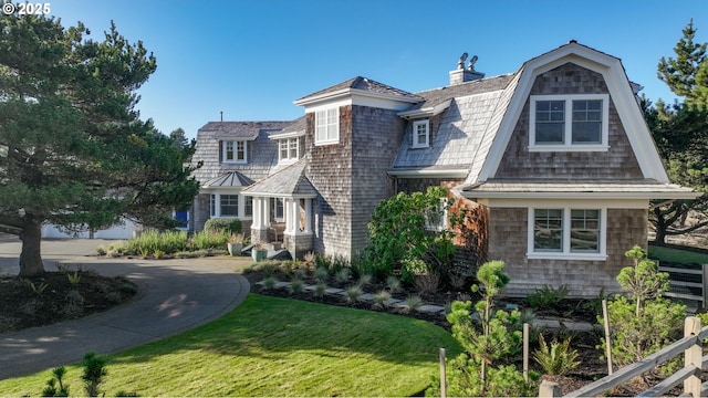 shingle-style home featuring a gambrel roof, a chimney, metal roof, a standing seam roof, and a front yard