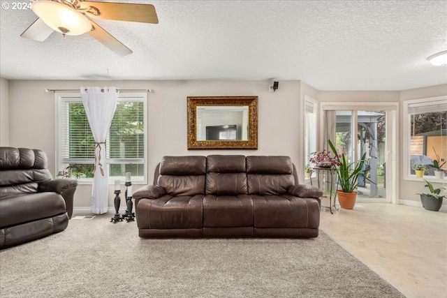 living room featuring baseboards, a textured ceiling, and ceiling fan