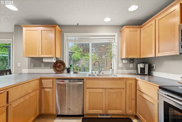 kitchen with light brown cabinetry, a sink, a textured ceiling, stainless steel appliances, and visible vents