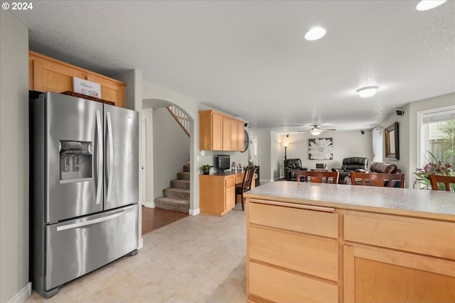 kitchen featuring a ceiling fan, stainless steel refrigerator with ice dispenser, light countertops, light floors, and light brown cabinets
