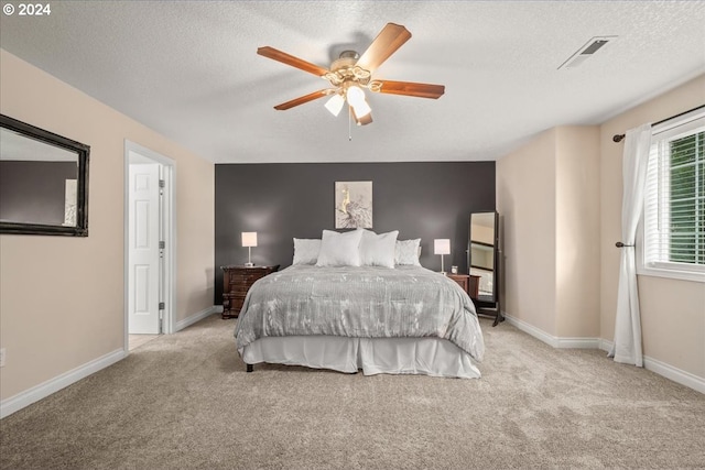 carpeted bedroom featuring baseboards, ceiling fan, a textured ceiling, and visible vents