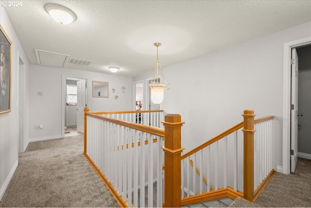 hall featuring carpet flooring, visible vents, an upstairs landing, and attic access
