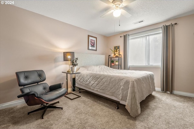 bedroom featuring a ceiling fan, a textured ceiling, visible vents, baseboards, and carpet flooring