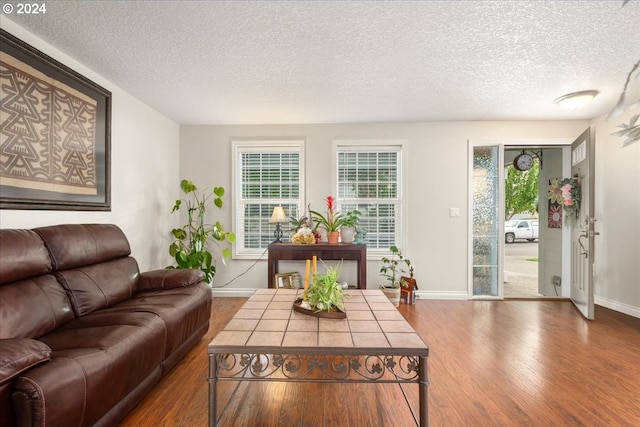 living area with a textured ceiling, baseboards, and wood finished floors