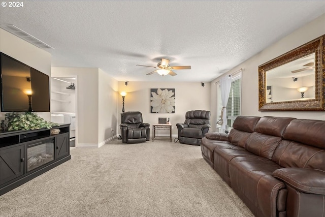 living area featuring a ceiling fan, a textured ceiling, light carpet, and baseboards