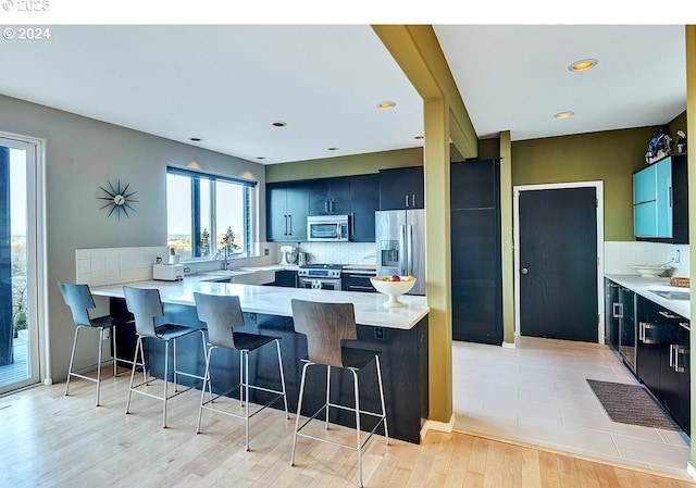 kitchen featuring appliances with stainless steel finishes, a breakfast bar, a peninsula, and decorative backsplash