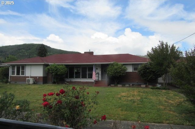 single story home with brick siding, a front lawn, and a mountain view