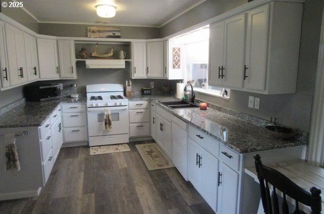 kitchen with white appliances, a sink, under cabinet range hood, dark wood-style flooring, and crown molding
