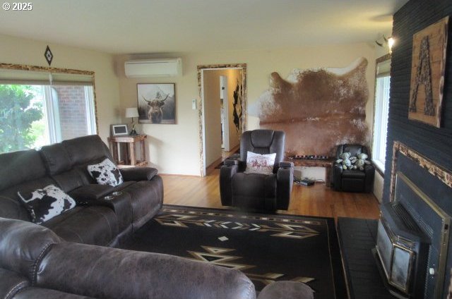 living area with a wall mounted AC and wood finished floors