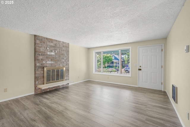 8419 SE Yamhill St, Portland, OR 97216 - unfurnished living room with a textured ceiling, wood finished floors, a fireplace, and baseboards