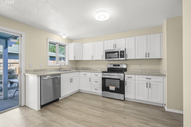 8419 SE Yamhill St, Portland, OR 97216 - kitchen with appliances with stainless steel finishes, a sink, white cabinets, and light wood-type flooring