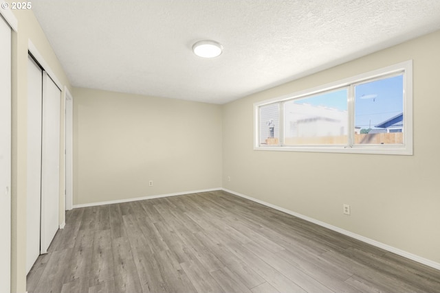 8419 SE Yamhill St, Portland, OR 97216 - unfurnished bedroom featuring wood finished floors, a closet, baseboards, and a textured ceiling