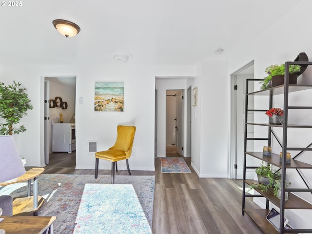 sitting room featuring baseboards, visible vents, wood finished floors, and washing machine and clothes dryer