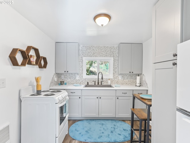 kitchen with white appliances, a sink, visible vents, and decorative backsplash