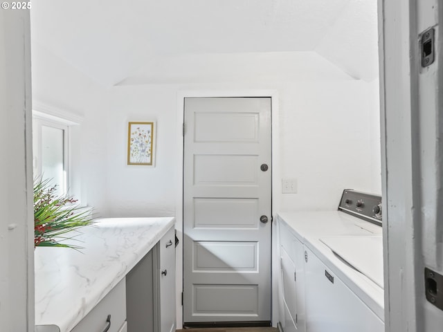 clothes washing area with separate washer and dryer and cabinet space