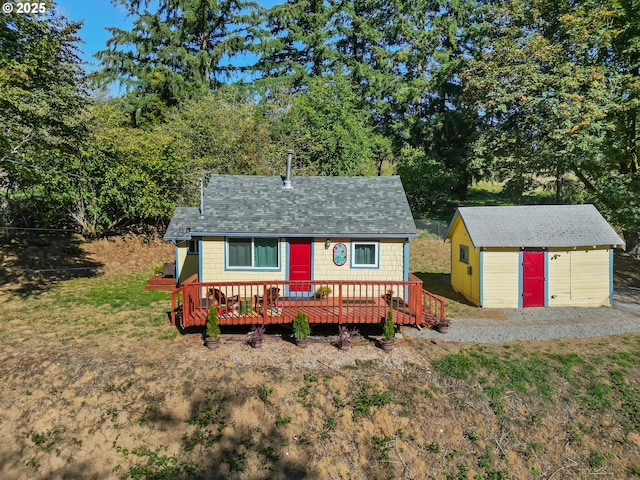 view of front of property with an outdoor structure, a wooden deck, and a shed