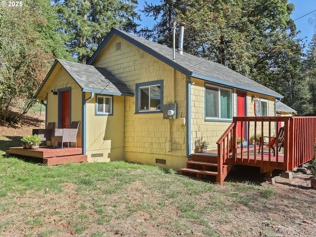 rear view of property featuring a deck, a shingled roof, crawl space, and a lawn