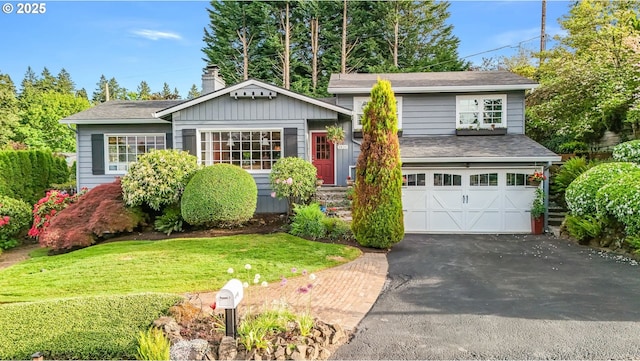 view of front facade with an attached garage, a chimney, asphalt driveway, a front lawn, and a shingled roof
