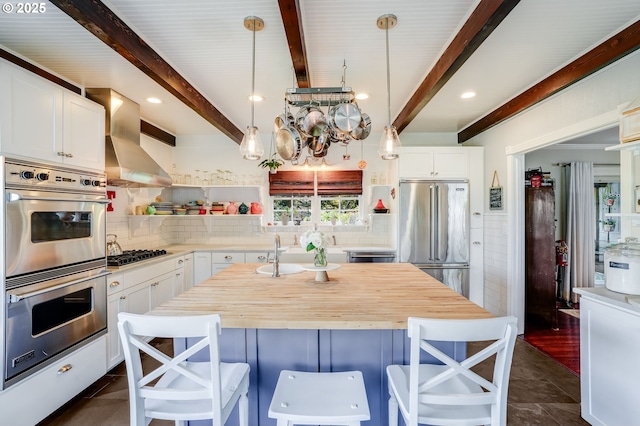 kitchen featuring stainless steel appliances, a sink, wooden counters, backsplash, and beam ceiling