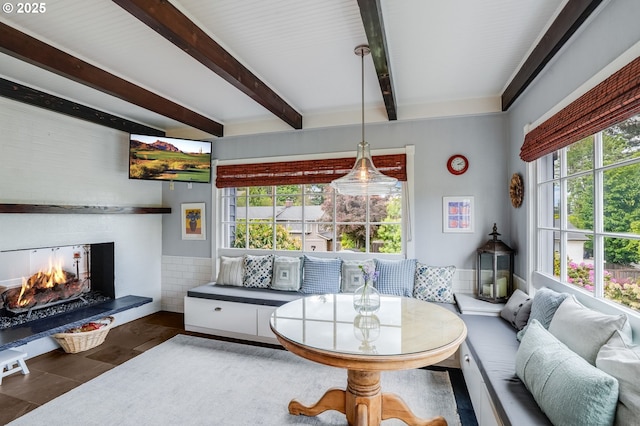 living room with a warm lit fireplace and beamed ceiling
