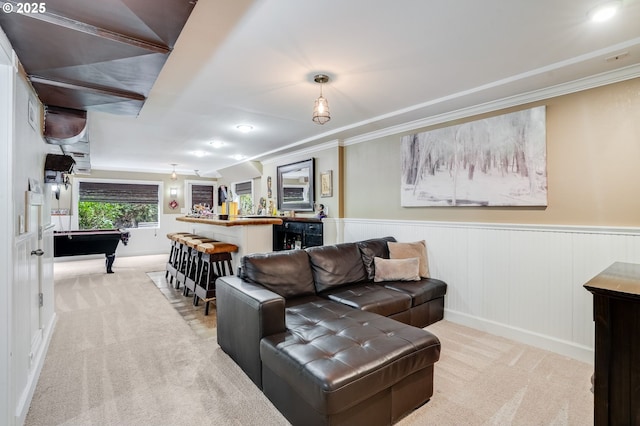 living room with bar with sink, light carpet, ornamental molding, wainscoting, and recessed lighting
