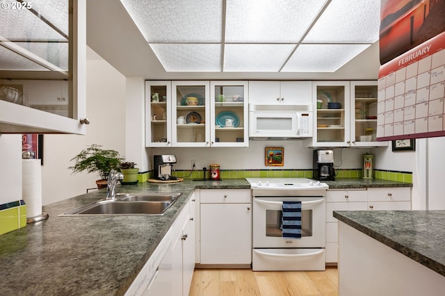6665 W Burnside Rd, Portland, OR 97210 - kitchen with white appliances, white cabinetry, dark countertops, light wood-type flooring, and glass insert cabinets