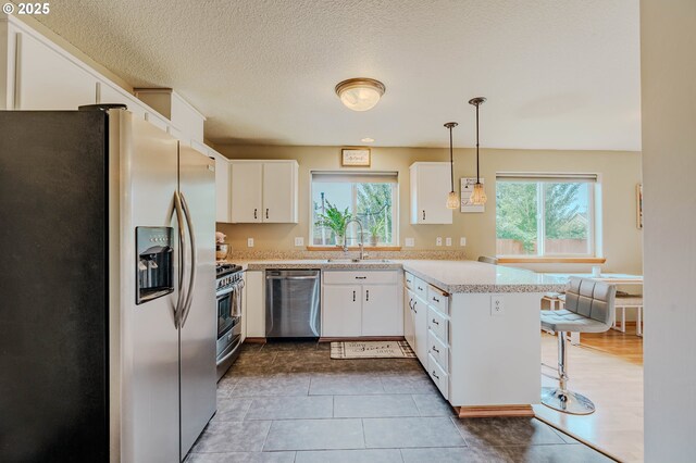 595 Cozy Way, Woodburn, OR 97071 - kitchen with appliances with stainless steel finishes, light countertops, a peninsula, white cabinetry, and a kitchen breakfast bar
