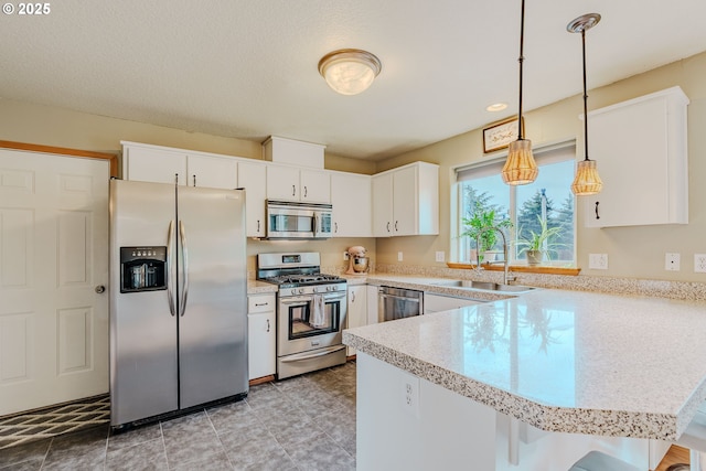 595 Cozy Way, Woodburn, OR 97071 - kitchen with stainless steel appliances, a peninsula, light countertops, white cabinetry, and pendant lighting