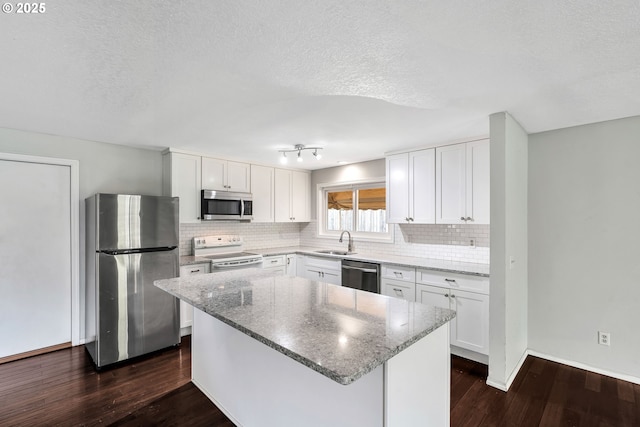 kitchen with stainless steel appliances, dark wood-style floors, light stone counters, backsplash, and white cabinets