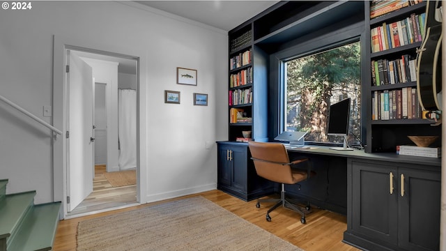 home office with light wood-style flooring, baseboards, and crown molding