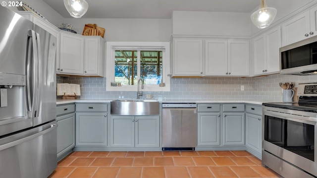 kitchen featuring appliances with stainless steel finishes, a sink, light countertops, and gray cabinets
