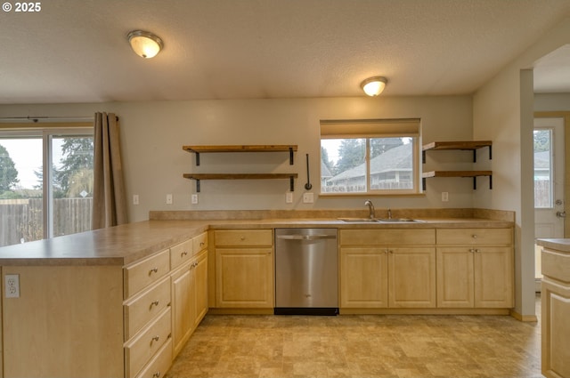 kitchen featuring light brown cabinetry, open shelves, a sink, stainless steel dishwasher, and a peninsula