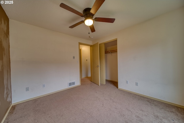 unfurnished bedroom with baseboards, visible vents, ceiling fan, a closet, and light carpet