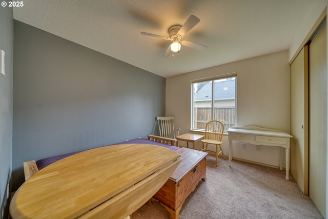 bedroom featuring ceiling fan, light colored carpet, a closet, and a textured ceiling