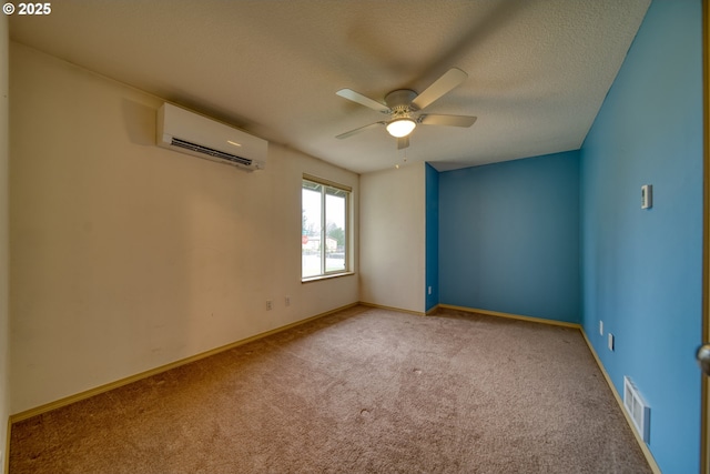 unfurnished room featuring baseboards, visible vents, a wall mounted air conditioner, a textured ceiling, and carpet flooring