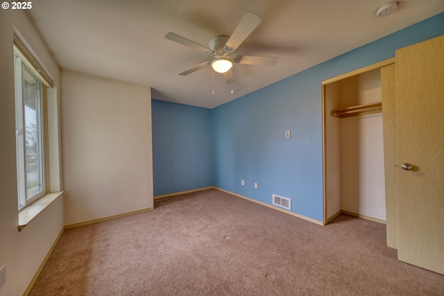 unfurnished bedroom with carpet, visible vents, baseboards, ceiling fan, and a closet