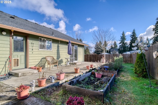 rear view of property featuring a garden, a patio, and a fenced backyard