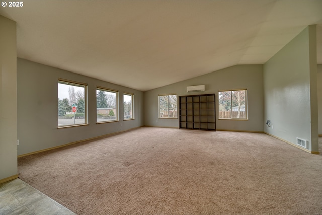 empty room featuring visible vents, a wall mounted air conditioner, lofted ceiling, and carpet floors