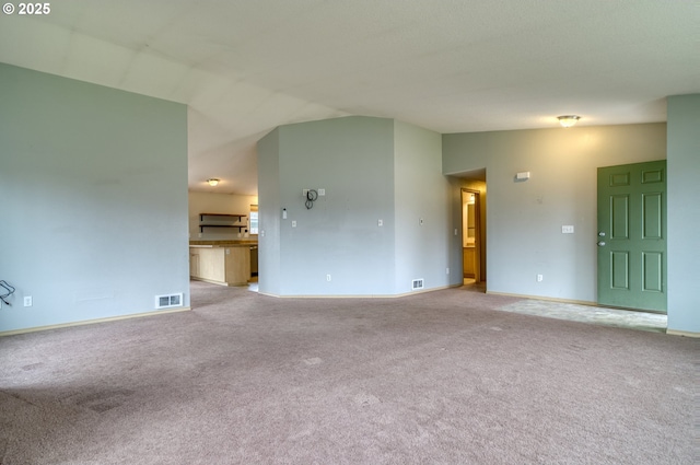 unfurnished living room with visible vents, light carpet, baseboards, and vaulted ceiling