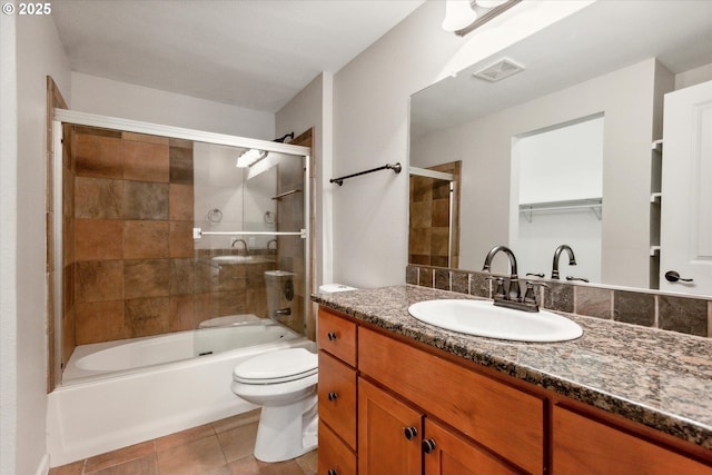 bathroom featuring visible vents, toilet, enclosed tub / shower combo, tile patterned flooring, and vanity