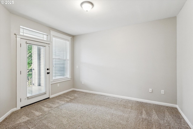 carpeted empty room featuring baseboards