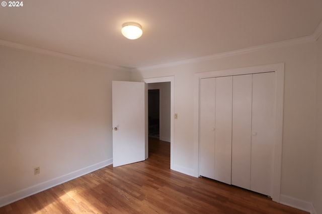 unfurnished bedroom with hardwood / wood-style flooring, ornamental molding, and a closet