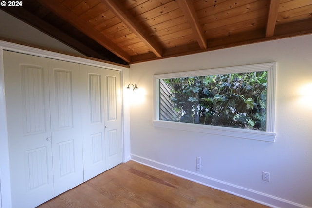 unfurnished bedroom featuring hardwood / wood-style floors, lofted ceiling with beams, wood ceiling, and multiple windows