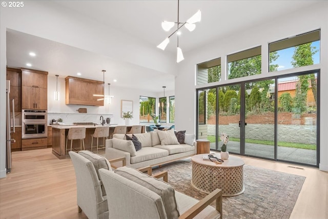 living area featuring an inviting chandelier, light wood-style flooring, recessed lighting, and a high ceiling