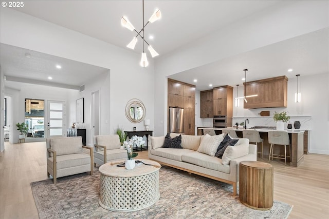 living room with visible vents, baseboards, light wood-style flooring, recessed lighting, and a chandelier